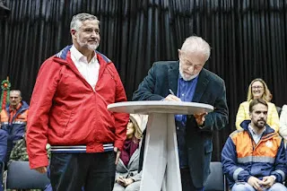 Rosário, ao fundo, sorrindo, tem dificuldade para explicar as promessas não cumpridas e feitas solenemente por Pimenta e Lula (na foto).